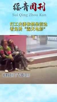打工夫妻依偎坐街边，看免费“露天电影”
