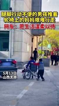 山西太原，一位行动不便的男孩推着坐在轮椅上的妈妈艰难行走