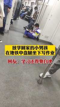 天津，地铁中一放学回家的小学生，盘腿坐地写作业。